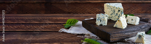 Sliced blue cheese on wooden background. Tasty dorblue on cutting board photo