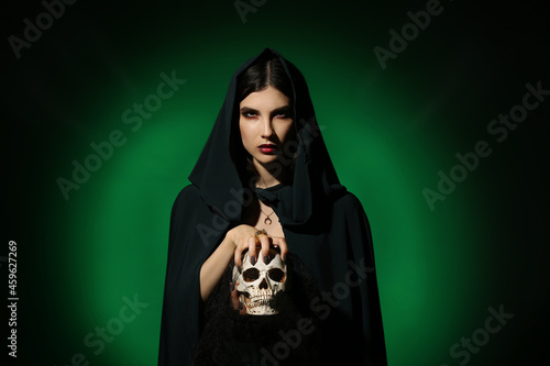 Obraz na plátně Young witch with skull on dark color background