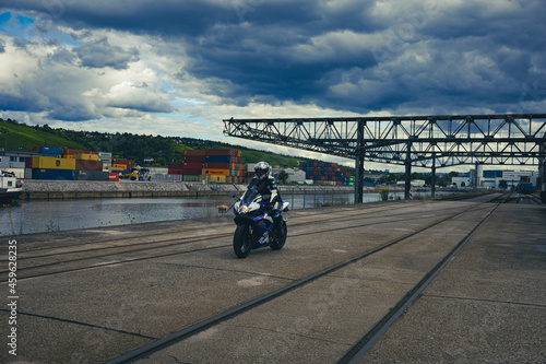 Motorradfahrer auf Schienen im Hafengebiet und Wolken im Hintergrund © carolindr18