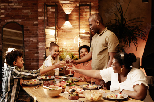 Obraz na płótnie Warm toned portrait of happy African-American family clinking glasses and toasti