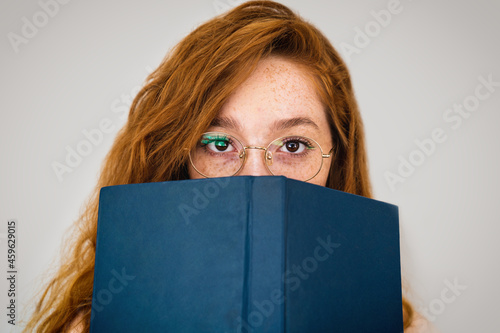 close up of an Intellectual young woman with a book in front of her face. literacy concept photo