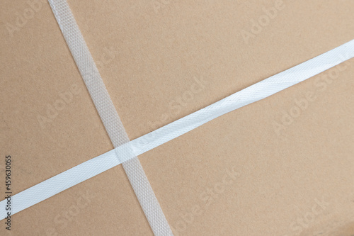 white packaging straps on brown parcel. freight parcel with plastic belt fastener..