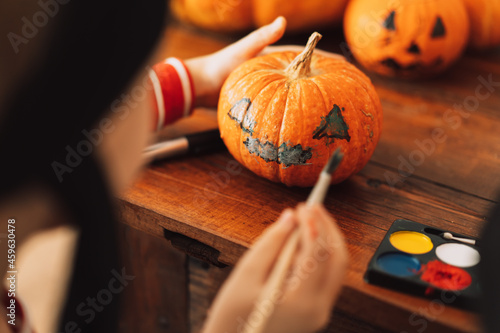 Boy dressed as pirate paints face on pumpkin photo