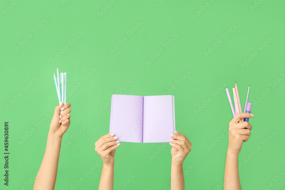 Many different hands with school supplies on green background Many different hands with school supplies on green background