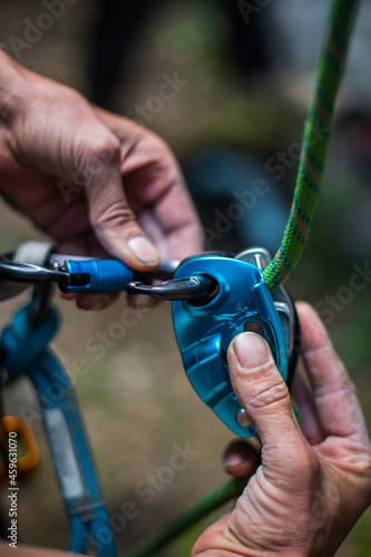 Man's hands operating a rock climbing belaying device © bizoo_n