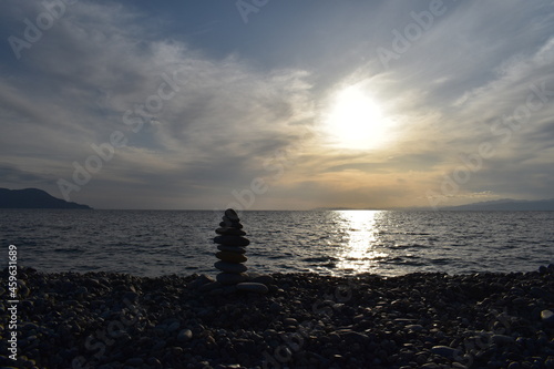 太陽と海、丸い石の海岸に丸い石を積む