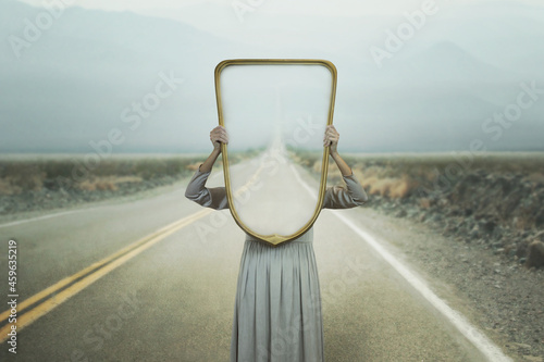 Photography the woman hides holding a mirror in front of her face; introspection path concep