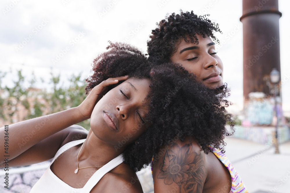 Afro woman with eyes closed leaning on shoulder of friend Afro woman with eyes closed leaning on shoulder of friend