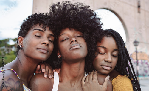 Young women with eyes closed leaning on shoulder's of female friend photo