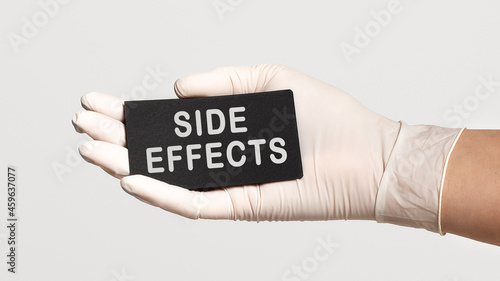 Fotografía Closeup of the hand in a white sterile glove holding a card with text - Side eff
