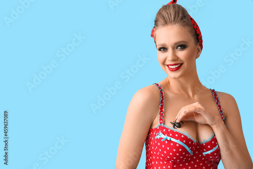 Sexy young woman with spider on her bust against color background photo