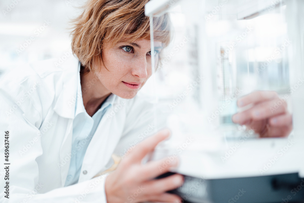 Female pharmacist looking at medical equipment in glass box Female pharmacist looking at medical equipment in glass box