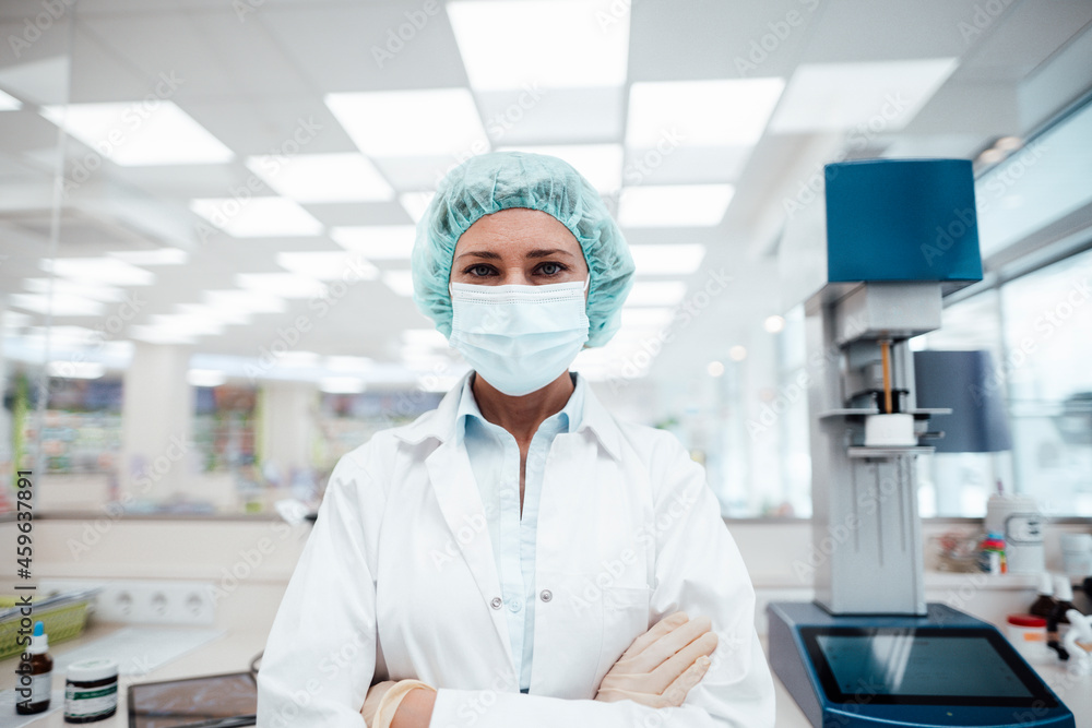 Female pharmacist with arms crossed standing at pharmacy store during pandemic Female pharmacist with arms crossed standing at pharmacy store during pandemic