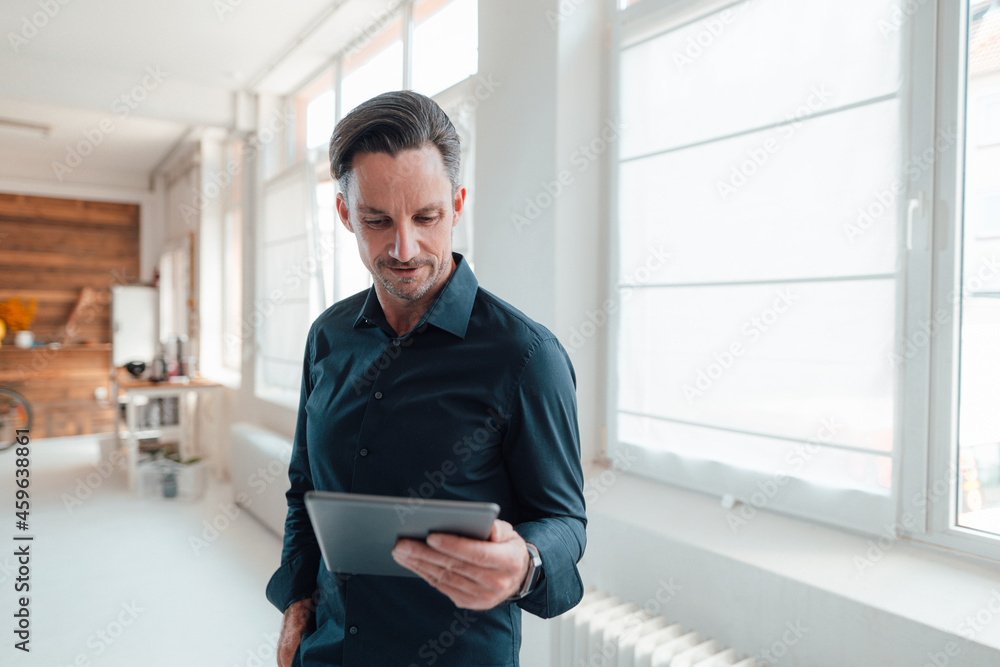 Mature male professional working on digital tablet in office Mature male professional working on digital tablet in office