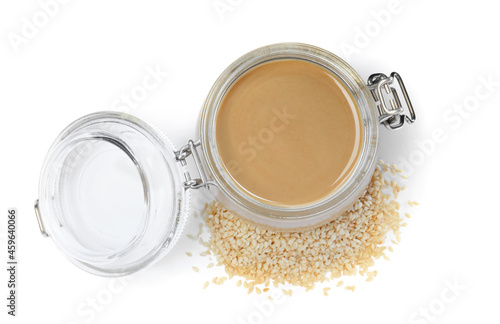 Tasty sesame paste in jar and seeds on white background, top view