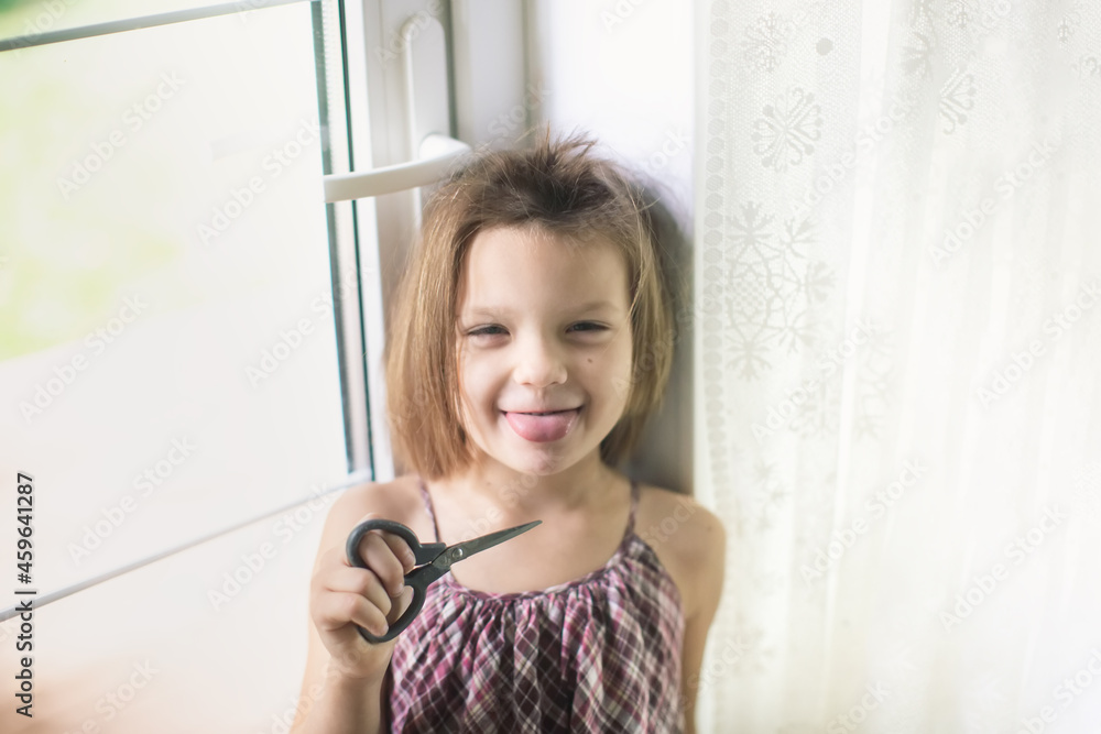 Happy caucasian girl child with scissors cuts off her hair, hooliganism and mischief child, child with a funny oblique haircut, child cut his hair Happy caucasian girl child with scissors cuts off her hair, hooliganism and mischief child, child with a funny oblique haircut, child cut his hair