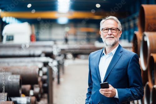 Male managing director with mobile phone at warehouse
