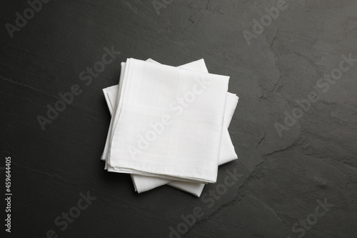Foto White handkerchiefs folded on black table, top view