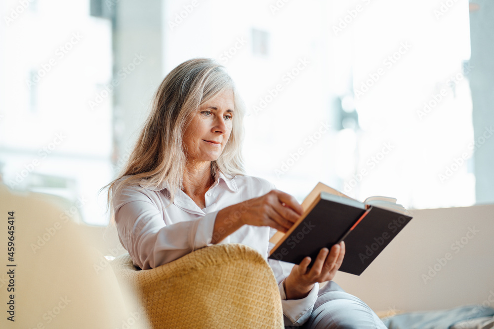 Mature woman reading book while sitting in cafe Mature woman reading book while sitting in cafe