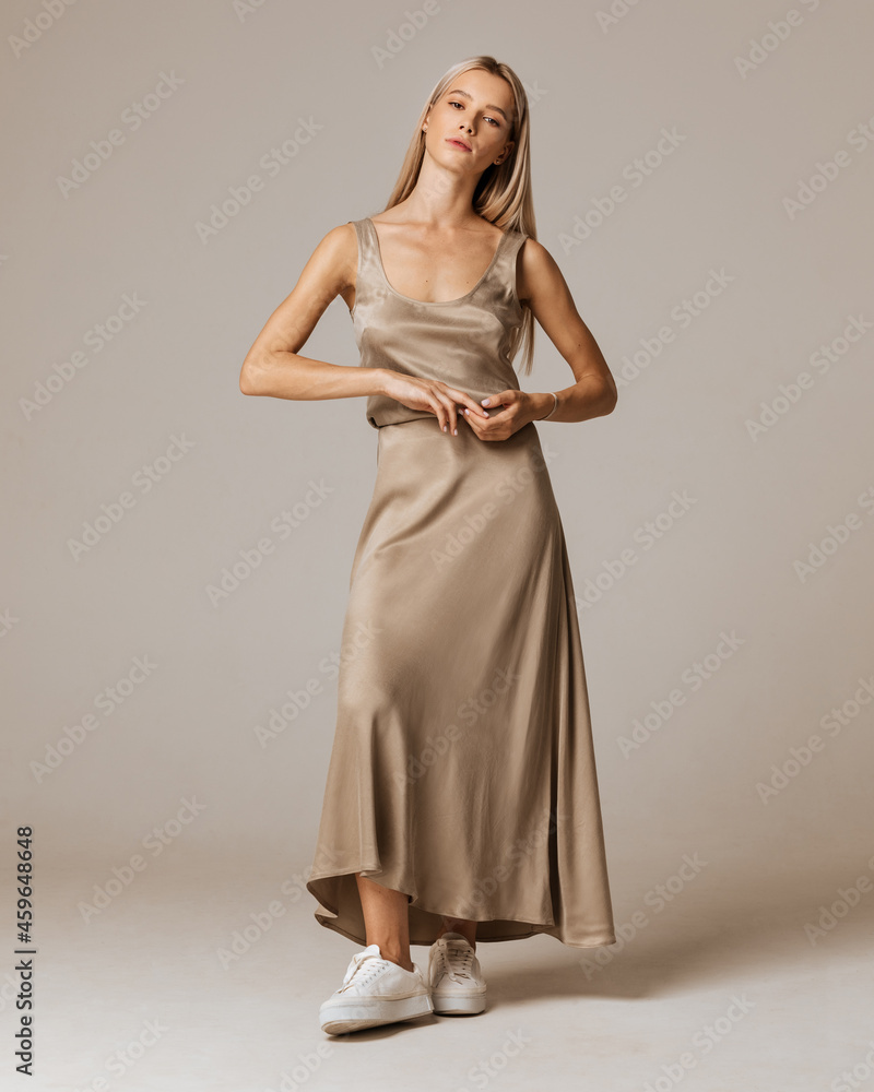 Studio photoshoot of a smiling young blond woman wearing casual clothing against a brown background. Natural makeup and hairstyle Studio photoshoot of a smiling young blond woman wearing casual clothing against a brown background. Natural makeup and hairstyle