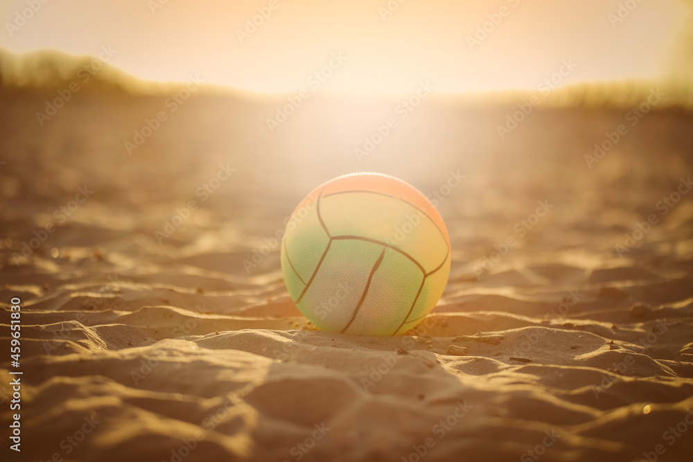 A colorful beach ball stands in the sand in the sunshine.