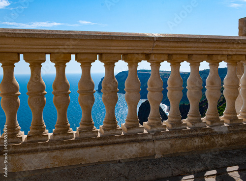 Beautiful old elegant balustrade made of white marble with dusty railings against the background of distant rocks and the blue sea