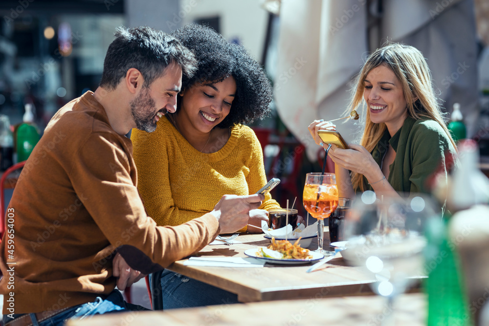 Male and female friends using mobile phones at restaurant Male and female friends using mobile phones at restaurant