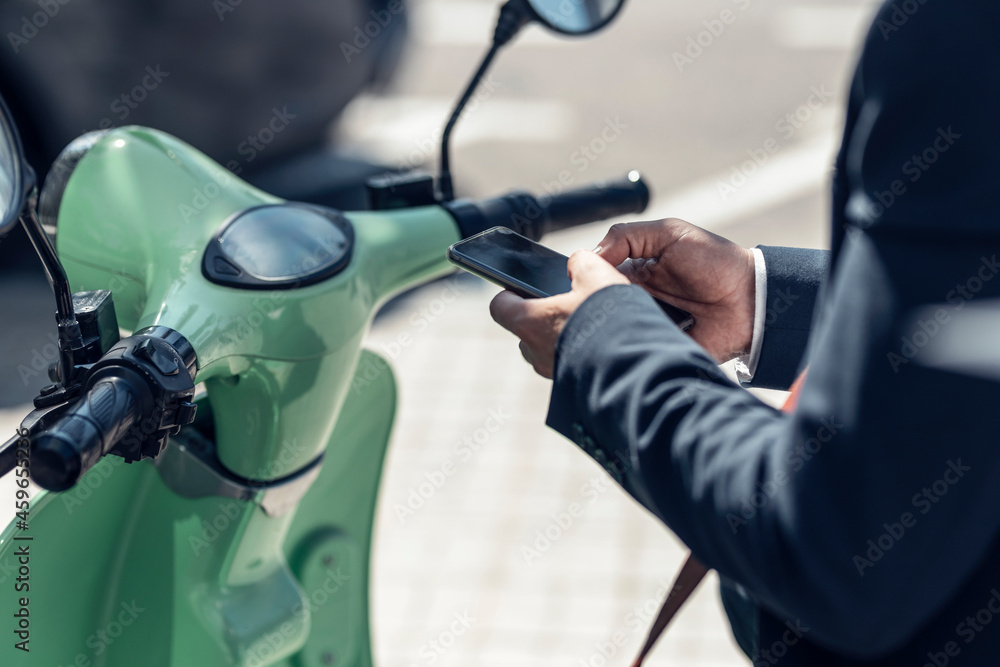 Male professional using smart phone on motor scooter Male professional using smart phone on motor scooter