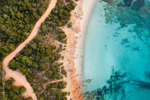 View from above, stunning aerial view of a green and rocky coastline with a white sand beach bathed by a turquoise, crystal clear water. Liscia Ruja, Costa Smeralda, Sardinia, Italy..