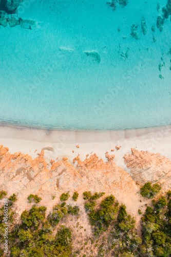 View from above, stunning aerial view of a green and rocky coastline with a white sand beach bathed by a turquoise, crystal clear water. Liscia Ruja, Costa Smeralda, Sardinia, Italy..