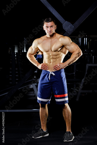 Young bodybuilder with great muscles posing in gym