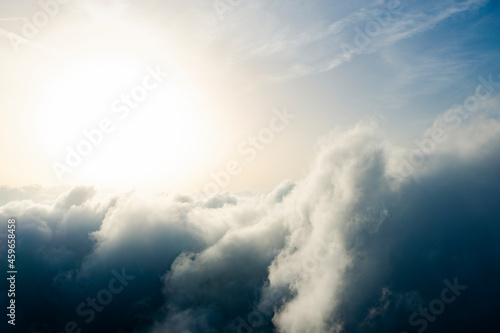 View from above, drone point of view, stunning aerial shot of some fluffy clouds with a bright sun.