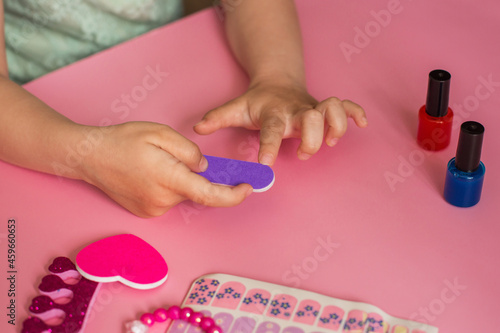 children's manicure. children's hands saws and paints nails. the game. baby cometic