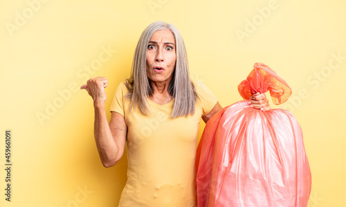 middle age pretty woman looking astonished in disbelief. plastic garbaje bag photo