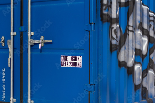 exterior of a blue metal shipping container with graffiti