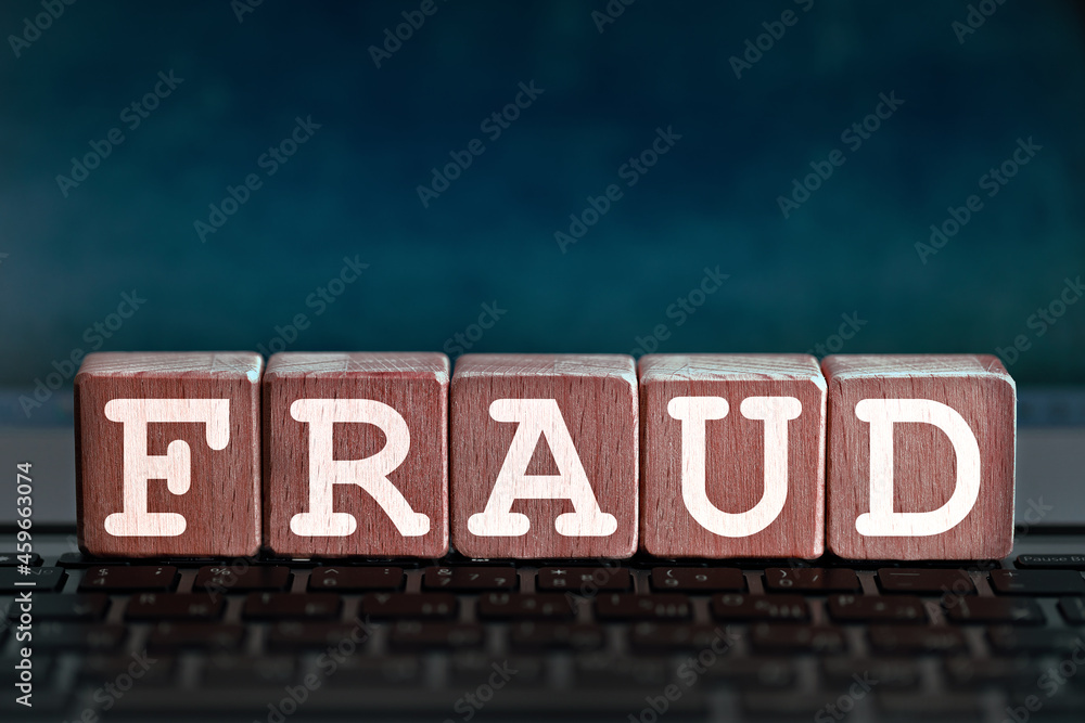 fraud theme. wooden cubes with the word fraud, on the background of laptop fraud theme. wooden cubes with the word fraud, on the background of laptop