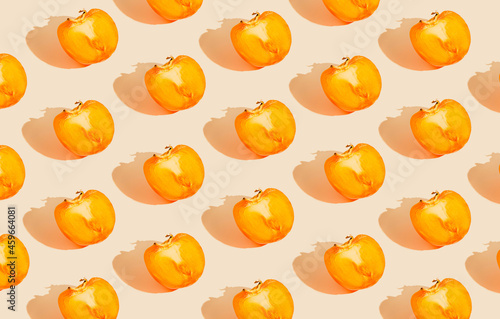 Fototapeta Naklejka Na Ścianę i Meble -  Creative pattern made of halves of persimmon fruits on pastel background with sunlit. Healthy food concept