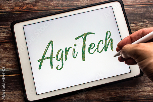 Closeup keyword Agritech (Agricultural technology) on tablet. Concept of technology in agriculture with the aim of improving yield, efficiency, and profitability. Man hand holding wireless stylus pen