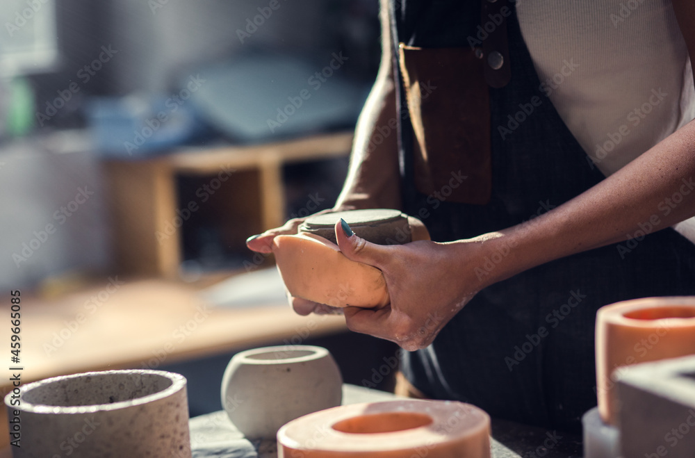 Close up of craftswoman hands making decorative concrete vase in her workshop.