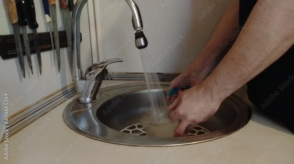 Man washing a cup in the sink at home Man washing a cup in the sink at home