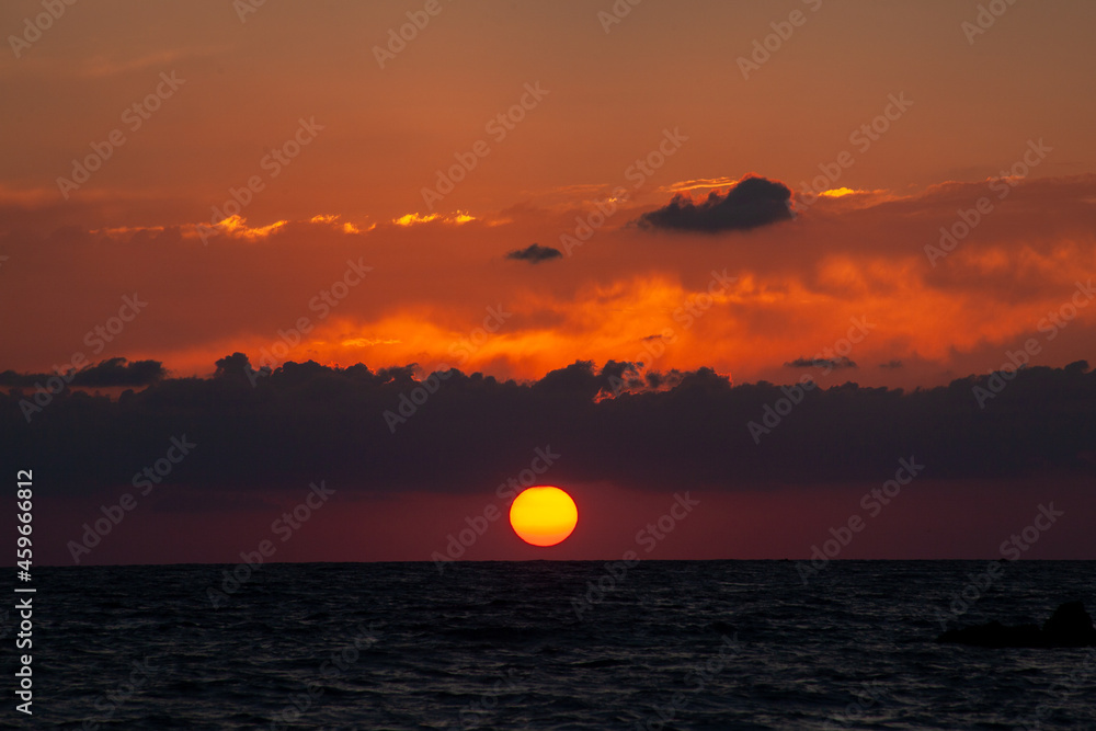 Sunset with huge sun falling on the sea at Aphrodite beach in Cyprus