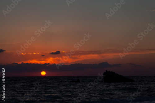 Sunset with huge sun falling on the sea at Aphrodite beach in Cyprus