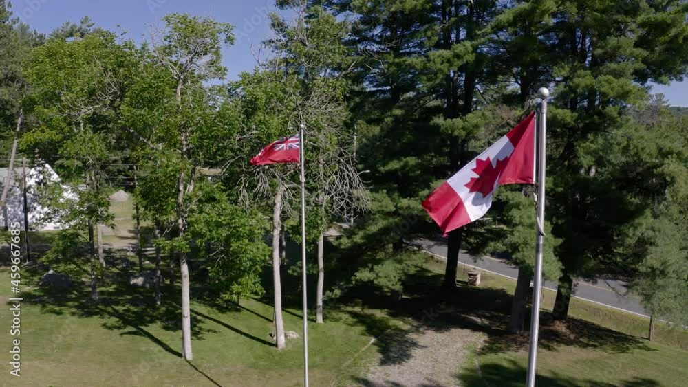 Canada and Ontario flags blowing in the wind at full mast on flag poles Canada and Ontario flags blowing in the wind at full mast on flag poles