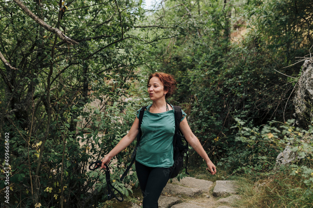 Smiling woman with pet leash walking in forest Smiling woman with pet leash walking in forest