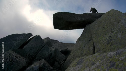 A man walking along a dangerous cantilever stone in the mountains photo