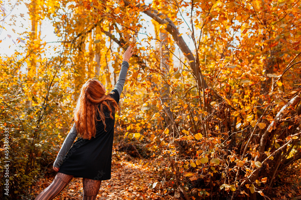 Woman stretching hand while standing in forest during autumn Woman stretching hand while standing in forest during autumn