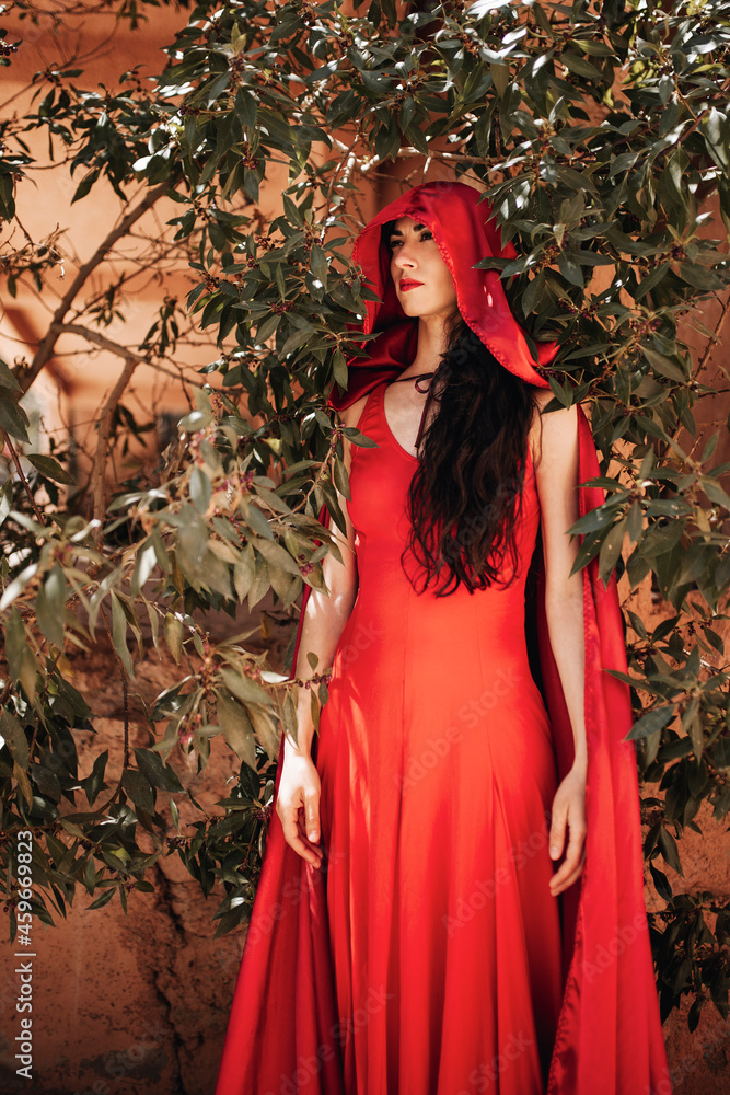 Woman in little red riding hood costume amidst plants Woman in little red riding hood costume amidst plants