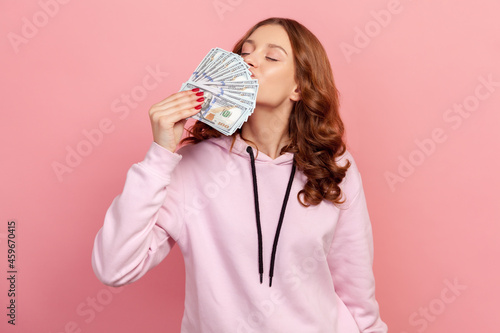 Tablou canvas Portrait of pleased brunette teenage female sniffing dollar banknotes, enjoying lottery win, success