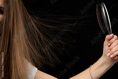 Woman with static long hair up in the air and a hair brush, on black background.