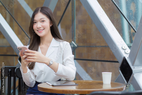 Asian businesswoman with long hair while working outside the office is using a smartphone to do business with a partner.
